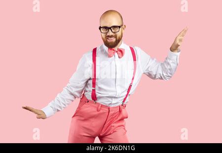 Happy young man in pink pants with suspenders dancing isolated on pink background Stock Photo