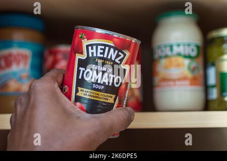 Adult male taking a can of Heinz tomato soup from cupboard Stock Photo