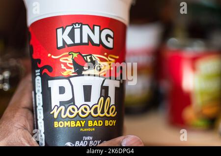 Adult male picking an Pot noodles from home food cupboard Stock Photo