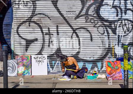 A female street artist paints in the sidewalk of Kensington Market Stock Photo
