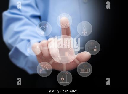 Man touches the icon of smart home service, including security, light, power, climate control, e.t.c. Concept of smart home / smart house. Stock Photo