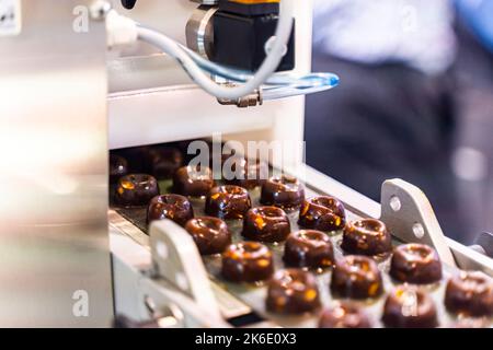 sweets production and industry concept - chocolate candies processing on conveyor at confectionery shop. High quality photo Stock Photo