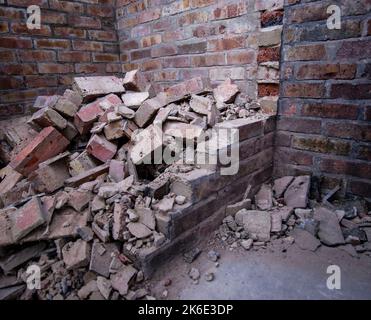 Pile of broken bricks and rubble inside a partially demolished brick-walled room during construction or renovation work Stock Photo