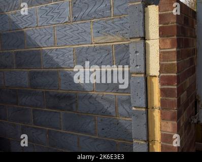Close up of a cross-section of a brick cavity wall revealing layers of insulation, blocks, and facing bricks in daylight Stock Photo