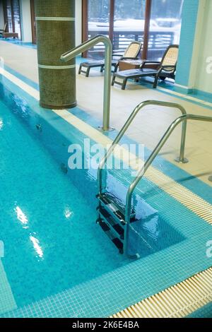 Pool ladder with stairs in empty pool for sport swimming training in leisure center.Ladder stainless handrails for descent into swimming pool Stock Photo