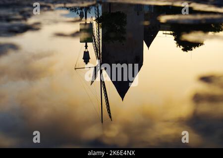 An upside down old windmill against bright sunset background Stock Photo