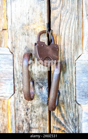 Old wooden door with rusty metal padlock close up Stock Photo