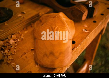 A hand carved wood Yankeys baseball hat rests on woodworking bench with tools at the League of New Hampshire Craftsman fair at Lake Sunapee, New Hamps Stock Photo