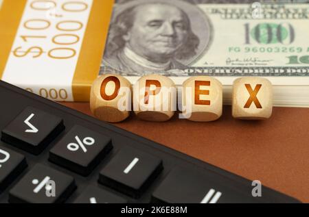 Business concept. On a brown surface are dollars, a calculator and wooden cubes with the inscription - OPEX Stock Photo