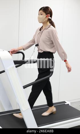 Tokyo, Japan. 13th Oct, 2022. Japan's electronics giant Kyocera employee walks on a treadmill to demonstrate the company's walk sensing and coaching system with three wearable sensors of earphone, bracelet and anklet in Tokyo on Thursday, October 13, 2022. The walk sensing system measures posture with tiny sensors and provide real time diagnosis and coaching through an earphone. Credit: Yoshio Tsunoda/AFLO/Alamy Live News Stock Photo