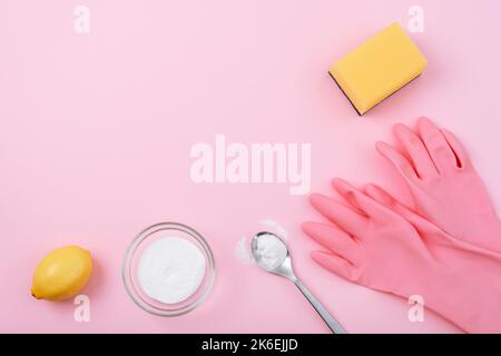 Cleaning gloves, yellow sponge, baking soda and lemon on pink background. Eco cleaning concept. Top view, flat lay, copy space. Stock Photo