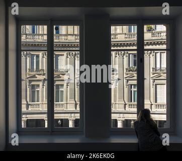 A woman looks out of a window in central Paris, France Stock Photo