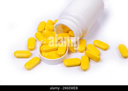 Medical white black orange pills spill out of a white jar on an isolated on white background Stock Photo