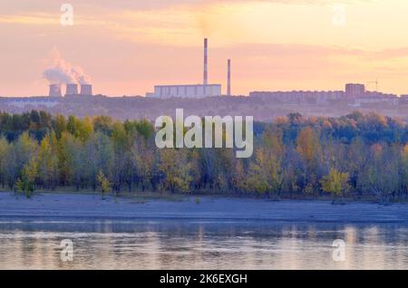 The shore of the Ob at dawn. Autumn forest by the river, CHP-5 pipes on the horizon. Novosibirsk, Siberia, Russia, 2022 Stock Photo