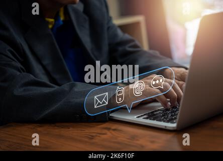 Hotline for customer support Contact us for people connection. Businessman using computer keyboard with email, phone, address, and chat message icons. Stock Photo