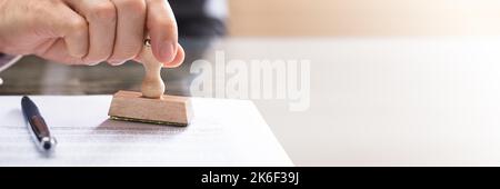 Person Hand Confidential Document Stamp Approval On Desk Stock Photo