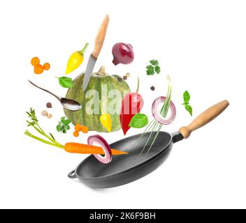 Flying fresh vegetables with utensils and frying pan on white background Stock Photo