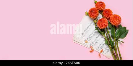 Beautiful dahlia flowers and music note sheets on pink background with space for text Stock Photo