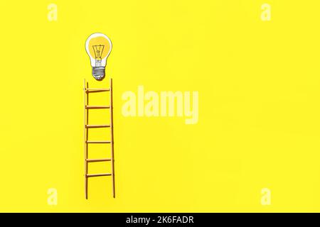 Ladder and light bulb on yellow background Stock Photo