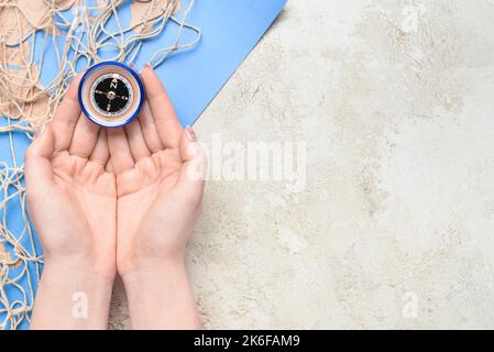 Female hands with vintage compass, fishnet and world map on light background Stock Photo