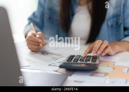Design building concept, Female architect is using calculator and sketching house plan on blueprint. Stock Photo
