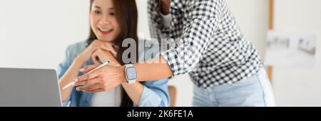Design building concept, Female architects explaining house plan and project on laptop to colleague. Stock Photo