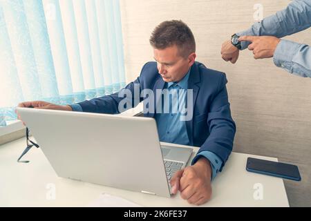 Keep track of time. man point at clock. Work time or working hours. Time management. Office life. Time for work. being late at work. boss scolds emplo Stock Photo