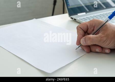 a hand with a pen in close-up signs an empty paper document. A man fills a white blank paper form with a pen close-up in bright sunlight. Stock Photo