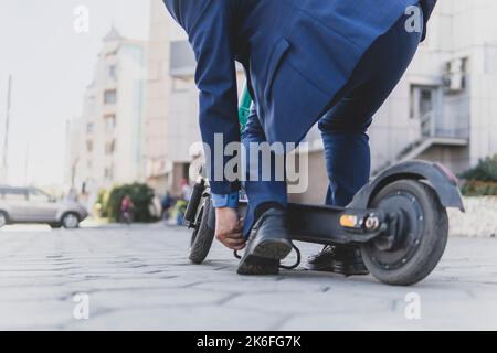 Fast and convenient. Close up shot of elegant, stylish middle aged business man standing with his electrical scooter outdoors. a businessman rents a s Stock Photo