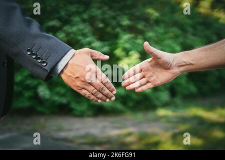 Farmer And Businessman Shaking Hands. Greeting handshake close-up on the background of the park. Meeting friends in nature. businessman and employee. Stock Photo