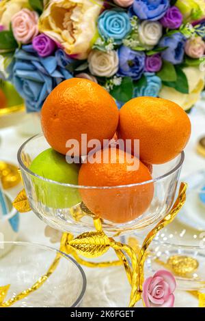 Fresh fruits in glass vase on festively decorated table. Stock Photo
