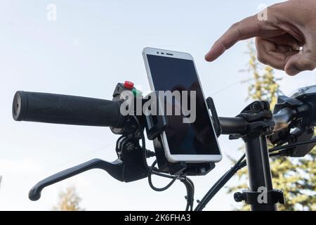 cyclist hands use gps navigator on smartphone while biking. man presses his finger on the smartphone screen. Stock Photo