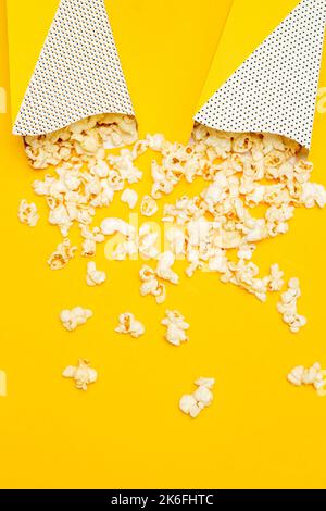Snack concept, Sweet popcorn spilled out from two paper cup on yellow background. Stock Photo