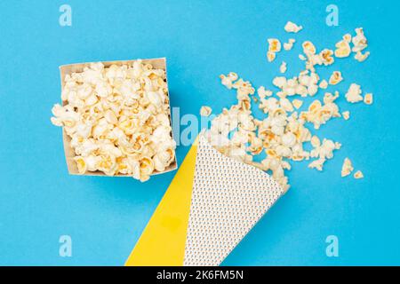 Snack concept, Sweet popcorn in paper cup and spill out from paper cup on light blue background. Stock Photo