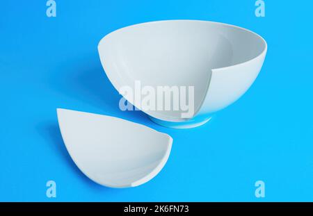 Side view of a broken white ceramic bowl on blue background. Stock Photo