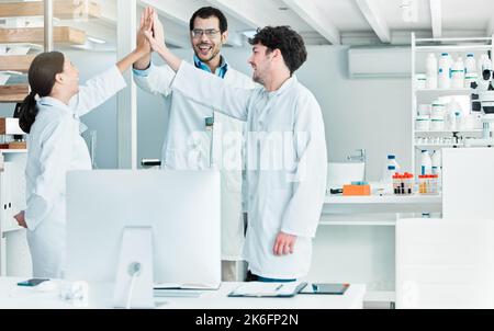Thrilled by their teams discovery. a group of young scientists giving each other a high five in a lab. Stock Photo