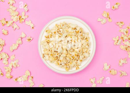 Snack concept, Sweet popcorn in white plate and falling on pink background. Stock Photo