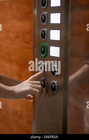 A woman's hand presses a button in the elevator to call for help. Modern elevator. Stock Photo