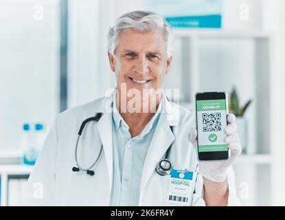 one tap is all it takes. a male doctor holding a smartphone depicting a QR code to be scanned. Stock Photo