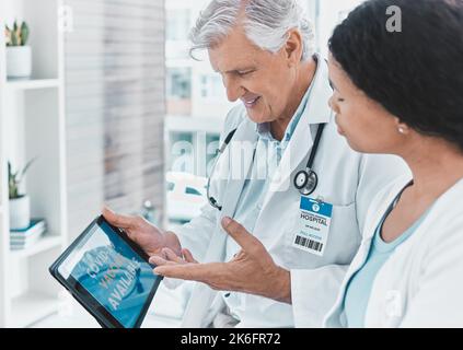 The new system is so simple. a senior doctor signing a patient up for vaccination using his digital tablet. Stock Photo