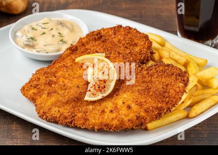 Chicken schnitzel with butter and potato salad on white porcelain plate Stock Photo