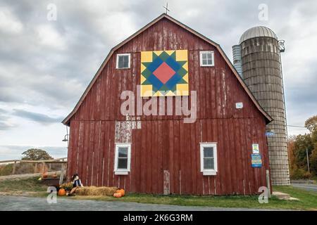 Rustic red barn and silo with a pretty barn quilt on it on a cloudy autumn afternoon in Shafer, Minnesota USA. Stock Photo