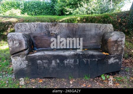Wooden bench in Bramshott village, Hampshire, UK, carved from the fallen hanging oak tree near the church, called Adrian's bench. Stock Photo