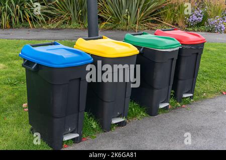 Colour coded black recycle bins for rubbish waste and litter of plastic bottles and cups and paper packaging with bags and tin cans as to not leave ca Stock Photo