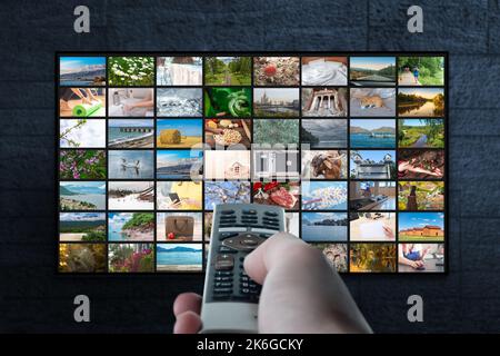 Multimedia streaming concept. Hand holding remote control. TV screen with lot of pictures. Video service with internet streaming multimedia shows, ser Stock Photo