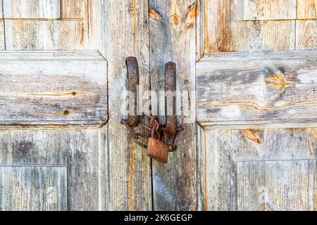 Old wooden door with rusty metal padlock close up Stock Photo