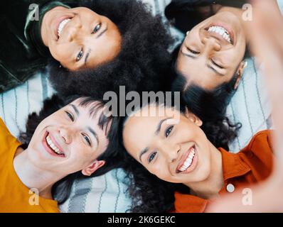 Friends are those rare people. female friends lying together on the blanket in a park. Stock Photo