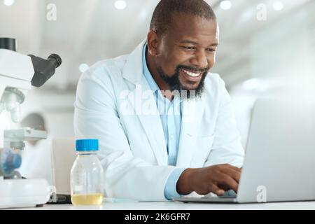 Updating the data with my findings. a handsome mature scientist sitting alone in his laboratory and using his laptop. Stock Photo