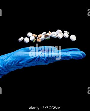 Medical pills on an isolated black background with reflection dropped from hand Stock Photo