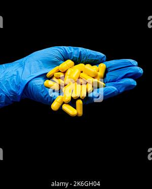 Medical pills on an isolated black background with reflection dropped from hand Stock Photo